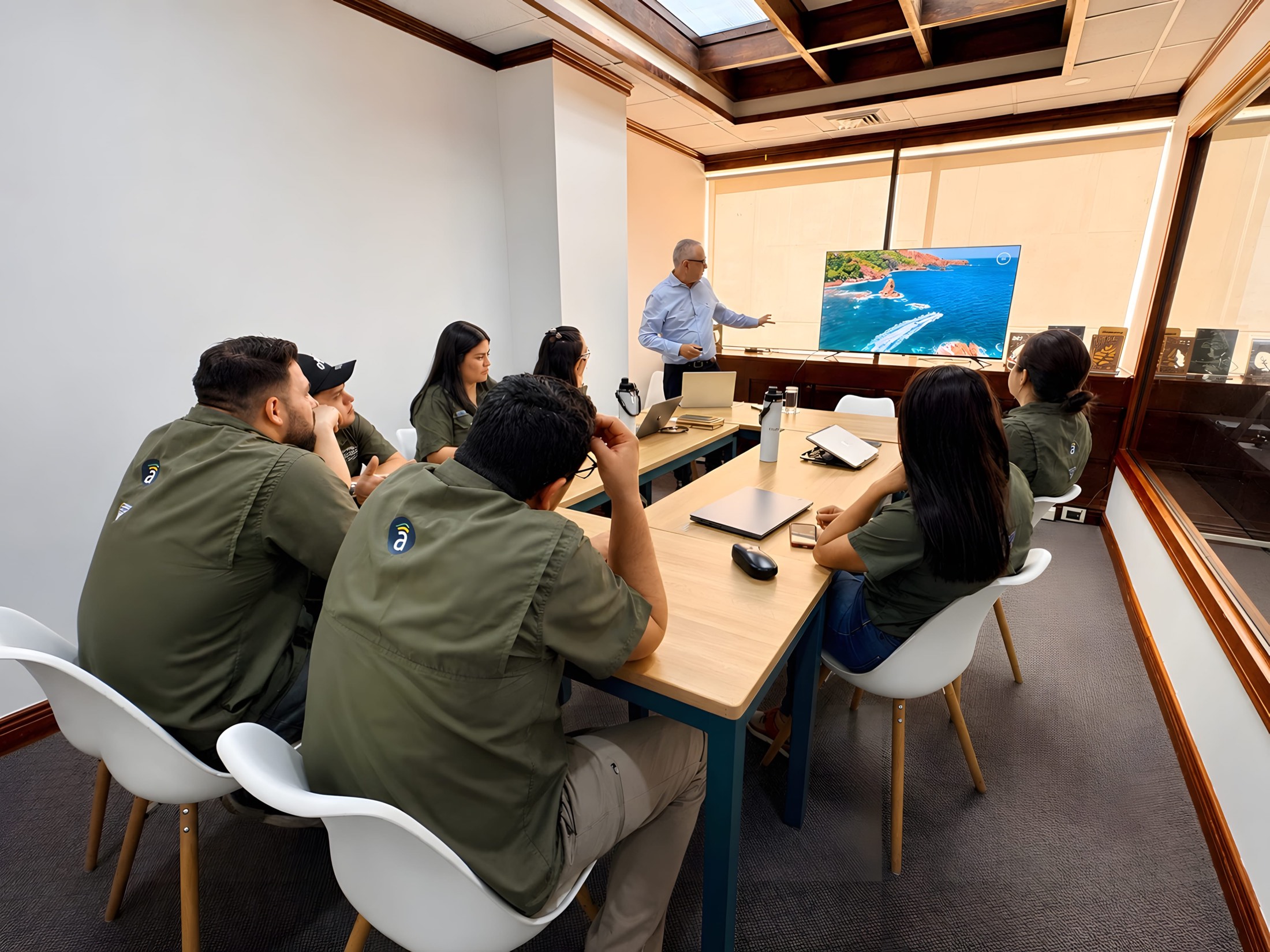 The Asuaire team in a working session at their Costa Rica office, an aerial of the coastline on screen.