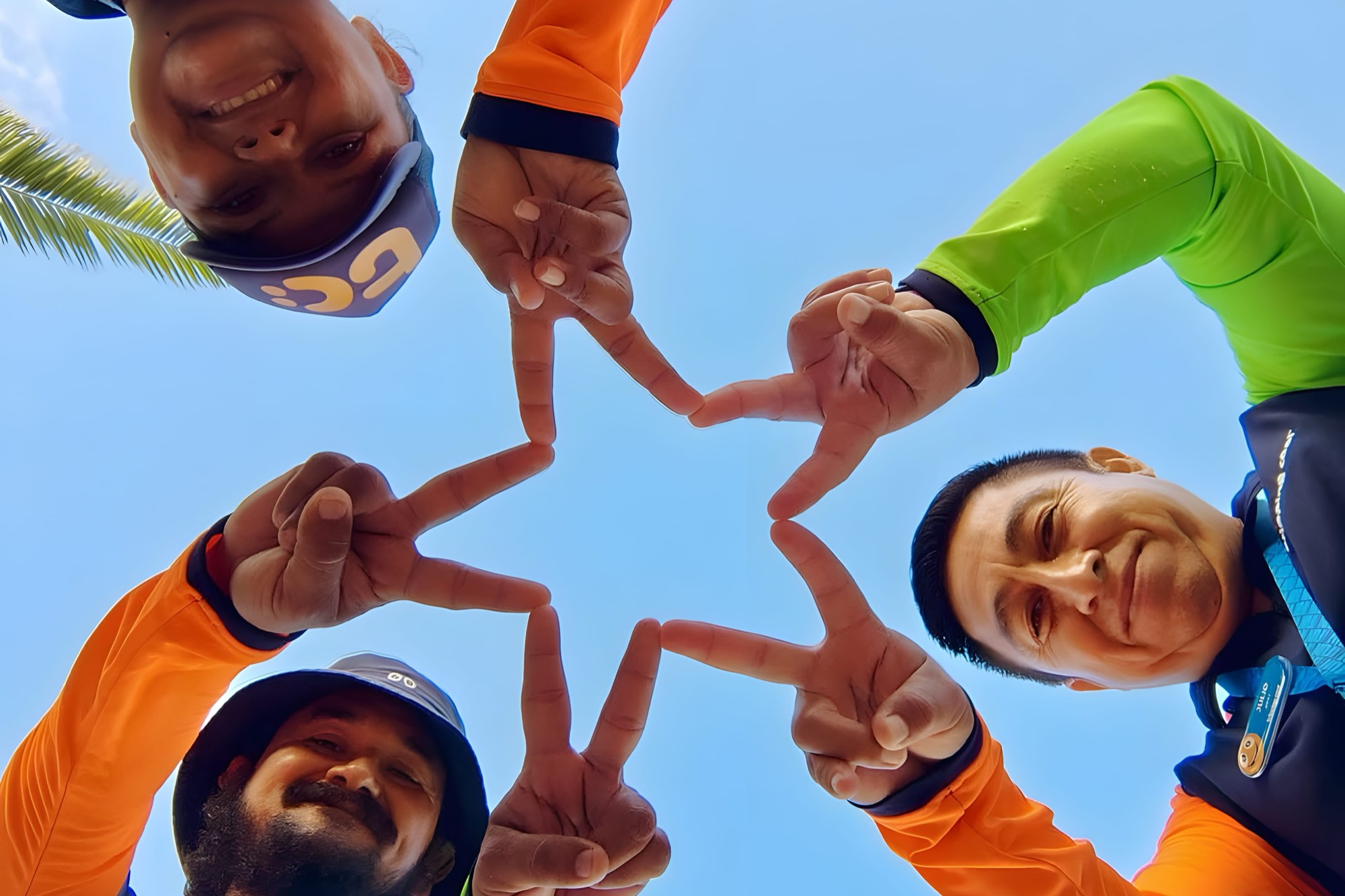 The Tripping Cool team on the beach in Cozumel, forming a star with their hands.